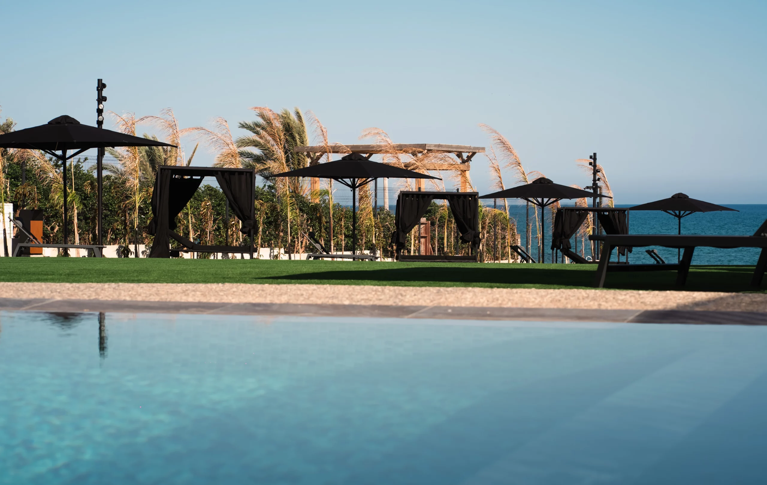 Swimming pool and outdoor relaxation spaces overlooking the Mediterranean Sea at NOE Suites in Agios Theodoros