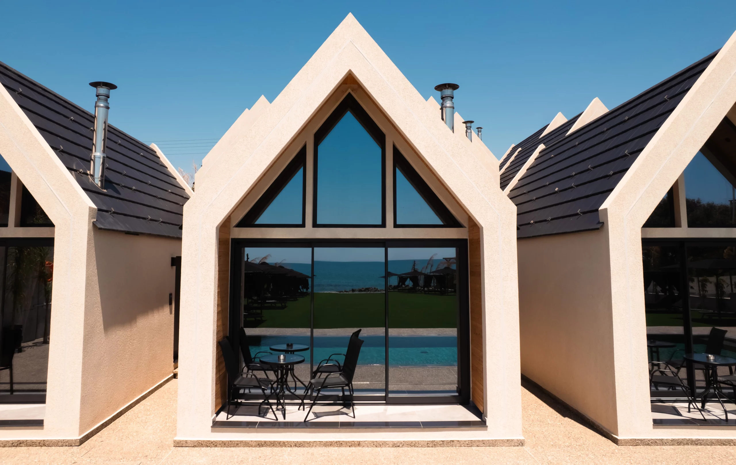 Exterior view of the suites at NOE Suites with outdoor seating, the pool and the sea beyond